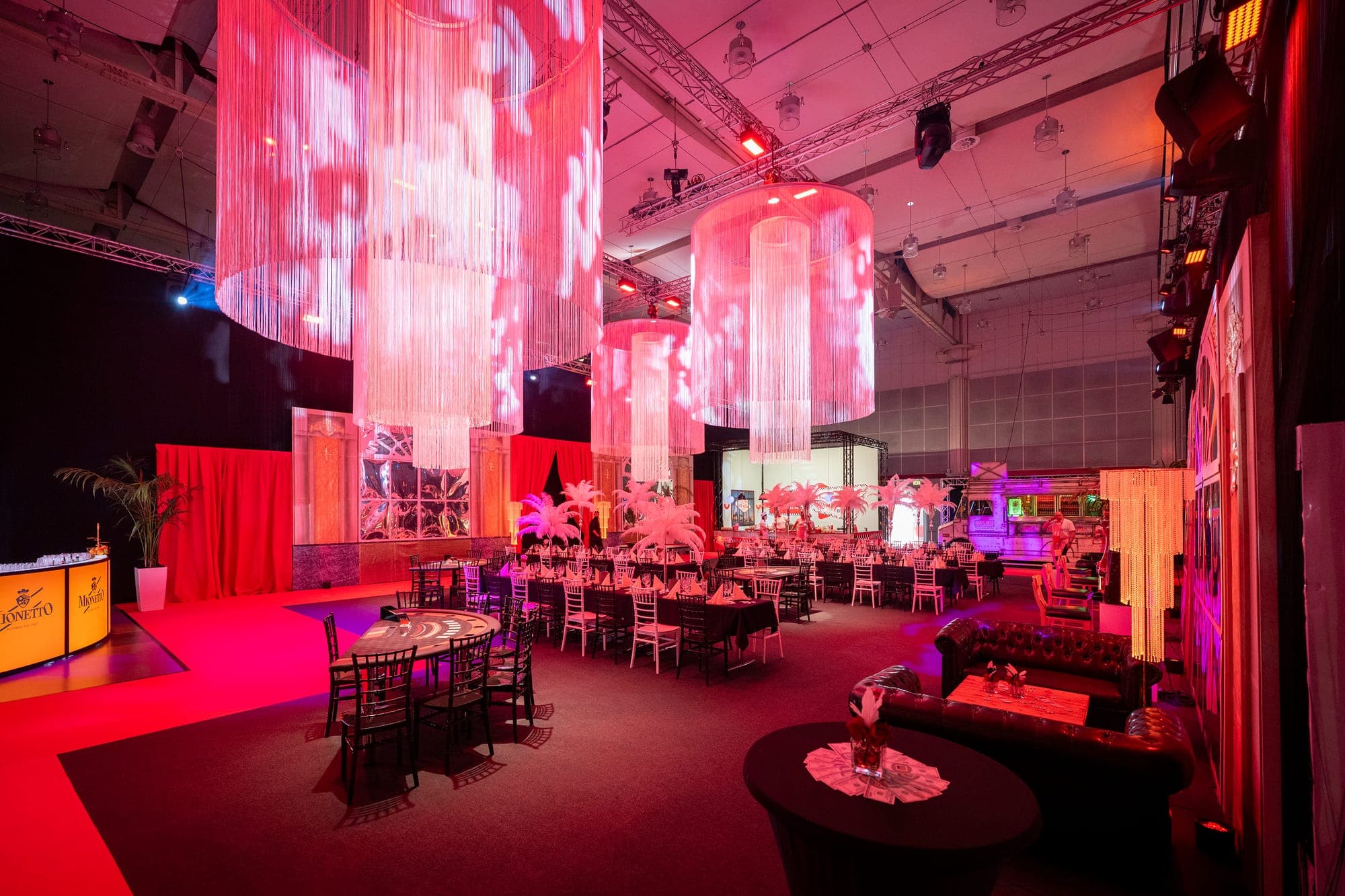 Festsaal mit Lichtinstallationen und Lounge-Bereich im roten Licht