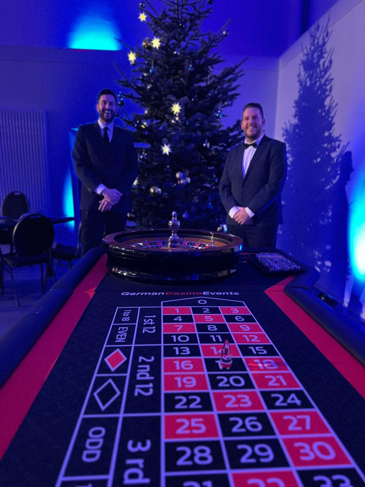 Zwei Croupiers am Roulettetisch vor einem Weihnachtsbaum